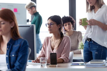 Businesswoman working at computer in an office, boss standing next to her