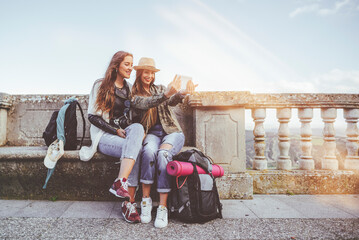 Fototapeta na wymiar Two happy young women on a trip taking a selfie with a tablet