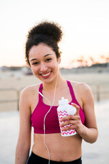 Portrait of smiing young woman with drinking bottle and earphones