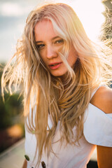 Portrait of blond young woman wearing white dress outdoors