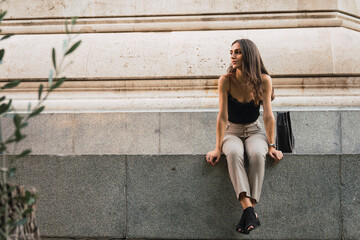 Young woman sitting on a wall waiting
