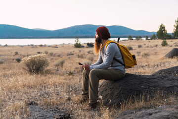 Fototapeta na wymiar USA, North California, bearded young man having a break on a hiking trip near Lassen Volcanic National Park