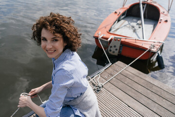 Woman standing on jetty with moored sailing boat