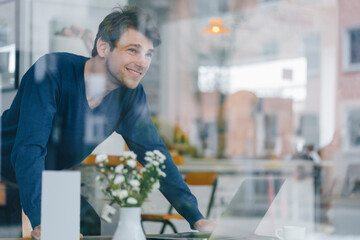 Smiling man in a cafe looking out of window