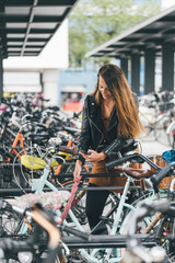 Fototapeta na wymiar Young woman with bicycle using cell phone in the city