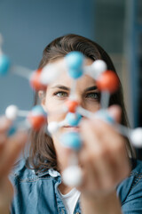 Female scientist studying molecule model, looking for solutions