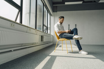 Mature businessman using cell phone in empty office