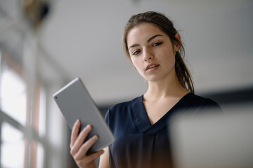 Portrait of young businesswoman with digital tablet in office