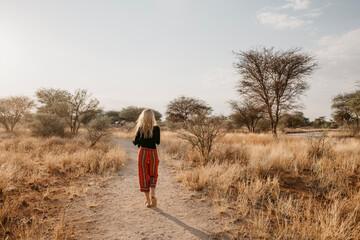 Africa, Namibia, blonde woman walking on way in grassland