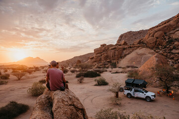 Namibia, Spitzkoppe, friends sitting on a rock watching the sunset