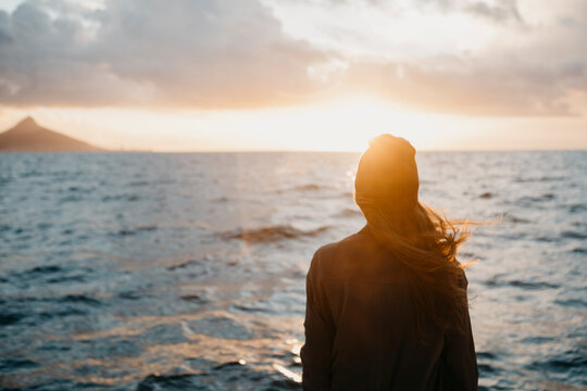 South Africa, young woman with woolly hat during boat trip at sunset