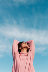 Relaxed young woman wearing pink turtleneck pullover enjoying fresh air