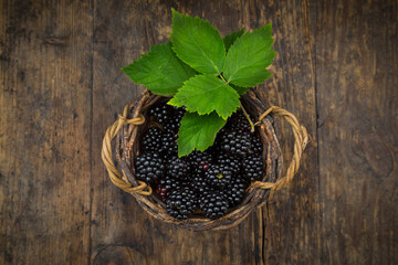 Wickerbasket of organic blackberries on wood