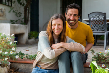 Smiling couple sitting on steps against farmhouse