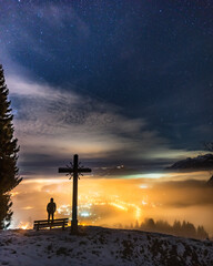 Silhouette of man admiring illuminated valley at night