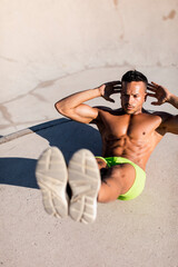 Barechested muscular man doing sit-ups in a skatepark