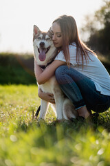 Young woman hugging her dog on a meadow