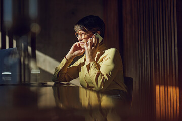 Businesswoman sitting in her sustainable office, talking on the phone