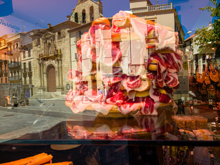bread and jamon are on the shop window, the city is reflected in the glass