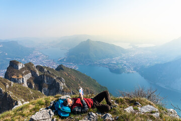Rear view of hiker reading a book on mountaintop, Orobie Alps, Lecco, Italy - obrazy, fototapety, plakaty