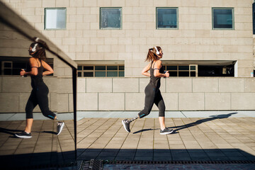 Sporty young woman with leg prosthesis running in the city