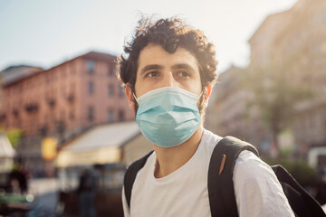 Close-up of thoughtful young man wearing face mask looking away in city