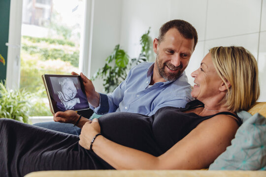 Mature pregnant couple watching a 3D image of their unborn child on tablet computer
