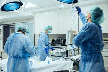 Doctor preparing IV drip in trauma room of a hospital - obrazy, fototapety, plakaty