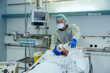 Doctor with bag valve mask caring for patient in emergency care unit of a hospital