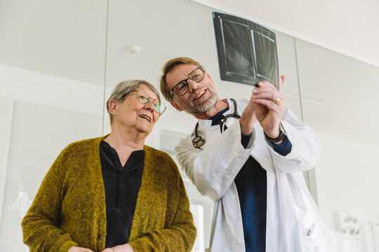 Doctor discussing x-ray image of broken hand with senior patient