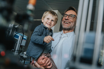 Fototapeta na wymiar Happy scientist father carrying son while standing in laboratory at factory