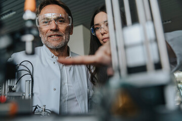 Close-up of scientists with protective eyewear examining machine in laboratory