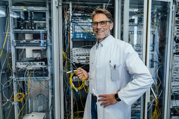 Male IT professional holding cables while standing in data center