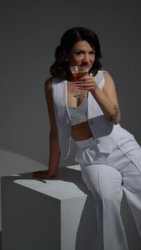 A brunette woman seductively drinks a martini