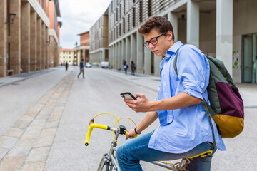 Young man on racing cycle looking at cell phone