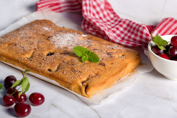 Sponge cake with a cherry on a light background. Homemade cooking