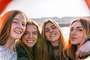 Portrait of four happy friends taking selfie