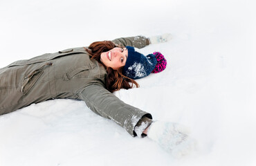 Fototapeta na wymiar Smiling young woman lying the snow