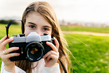 Portrait of a girl holding an old-fashioned camera outdoors