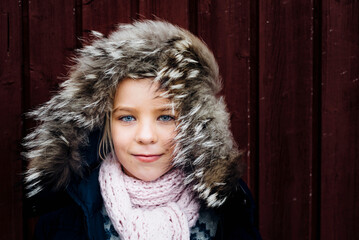 Portrait of a little girl wearing windswept fur hood