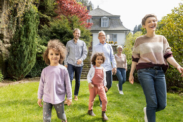 Happy extended family walking in garden of their home