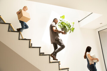 Family carrying various objects while moving down on steps in new home