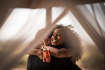 Happy woman holding fresh ice tea drink hugging man