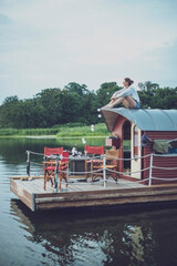 Mid adult woman sitting on roof of houseboat during sunset
