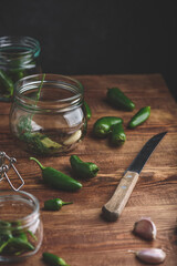 Preservation of Jalapeno Peppers in Jars with Herbs and Garlic on Wooden Table. Copy Space