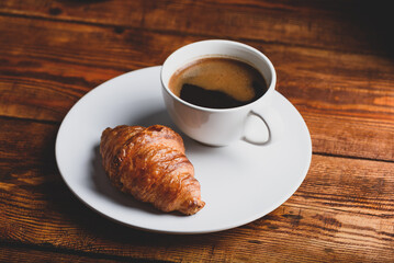 Cup of Black Coffee and Fresh Croissant on Rustic Table