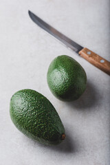 Two green avocados with knife
