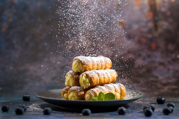 Delicious puff pastry tubes filled with custard. Powdered Sugar - obrazy, fototapety, plakaty