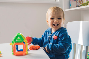 Portrait of laughing baby girl playing with modeling clay