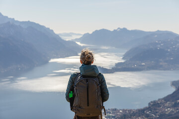 Italy, Como, Lecco, woman on a hiking trip in the mountains above Lake Como enjoying the view - obrazy, fototapety, plakaty